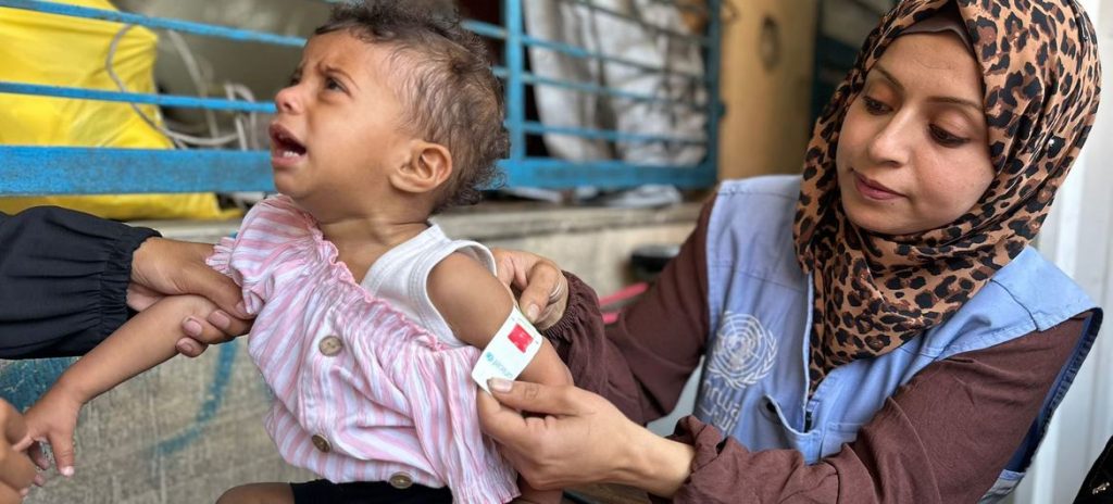 A UNRWA worker in Gaza checks a child for signs of malnutrition.