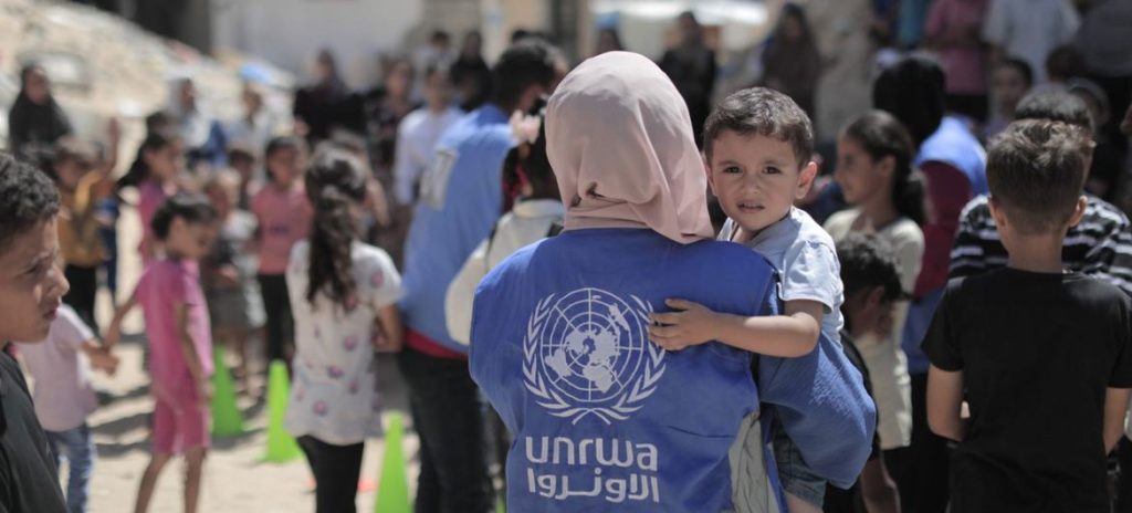 An UNRWA worker carries a young boy in Gaza.