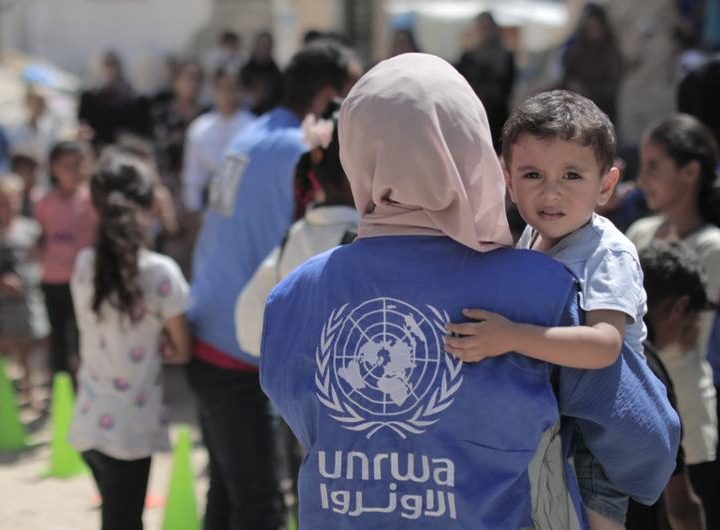 An UNRWA worker carries a young boy in Gaza.